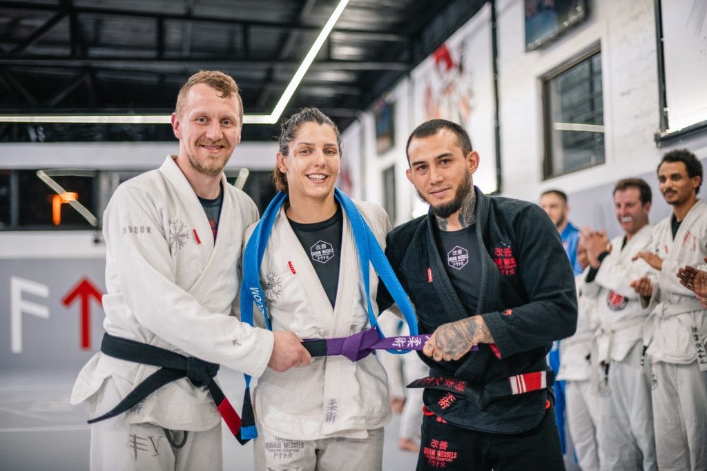 Warren King (left) & Richie Quan (right) award Monique van Staden her purple belt in Brazilian Jiu JItsu
